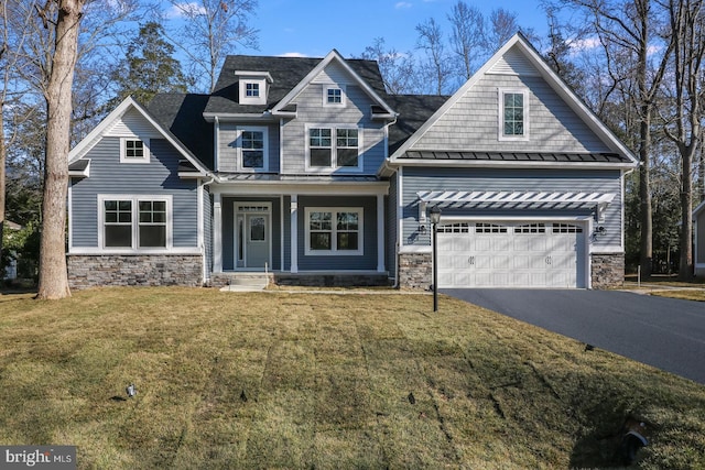 craftsman-style home featuring stone siding, a front lawn, a standing seam roof, and aphalt driveway