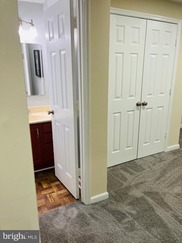 hallway with sink and dark colored carpet