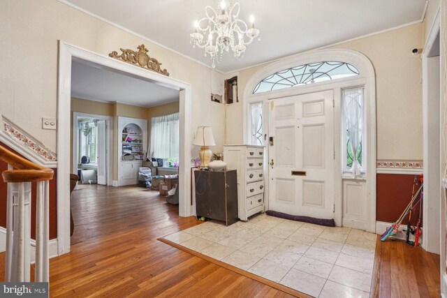 entryway featuring ornamental molding, light hardwood / wood-style flooring, and a notable chandelier