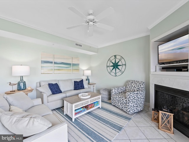 tiled living room with ornamental molding, a high end fireplace, and ceiling fan