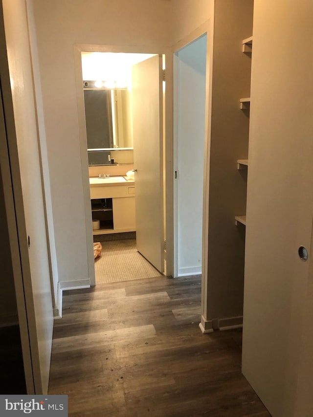 hallway featuring dark wood-type flooring and a sink