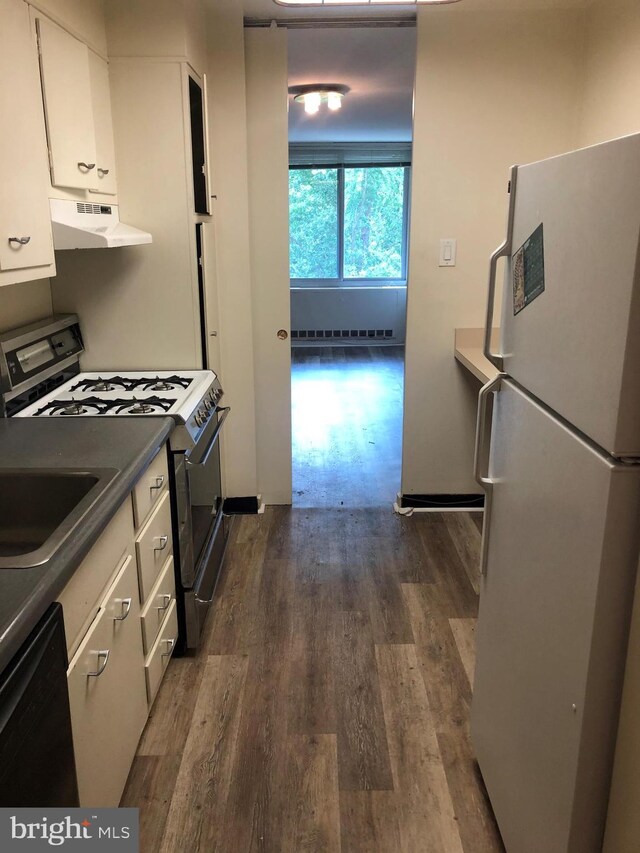 kitchen with white cabinetry, wall chimney range hood, dark wood-type flooring, and white appliances