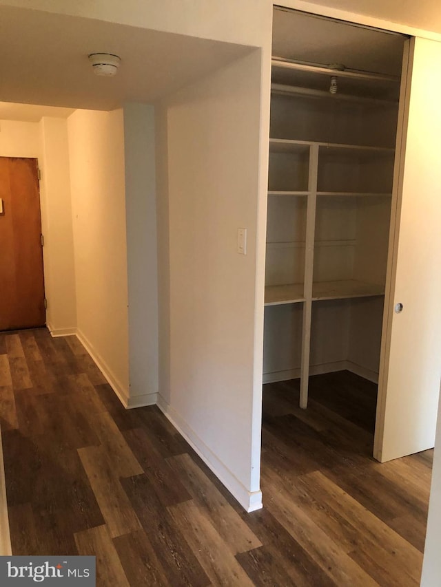 hallway with dark wood-style floors and baseboards