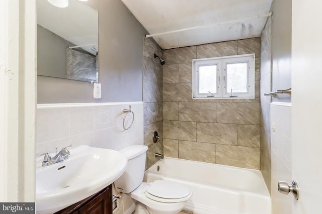 full bathroom featuring tiled shower / bath, vanity, tile walls, and toilet