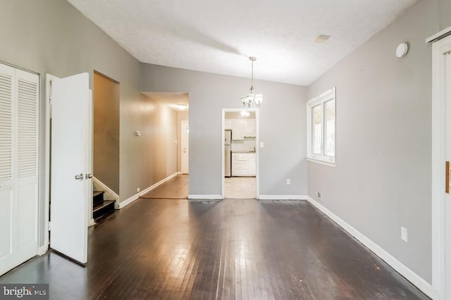 unfurnished dining area featuring an inviting chandelier, lofted ceiling, and dark hardwood / wood-style flooring