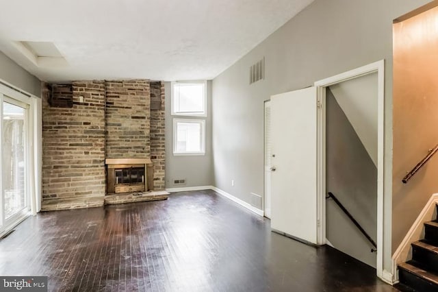 unfurnished living room featuring dark wood-type flooring and a stone fireplace