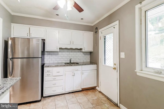 kitchen with plenty of natural light, white cabinets, stainless steel fridge, and sink