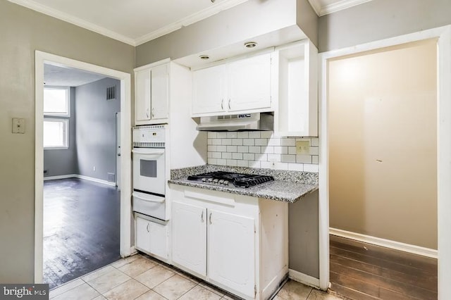 kitchen with oven, white cabinets, stainless steel gas cooktop, light hardwood / wood-style flooring, and ornamental molding