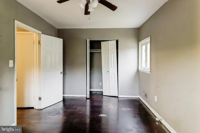 unfurnished bedroom featuring ceiling fan, dark wood-type flooring, and a closet