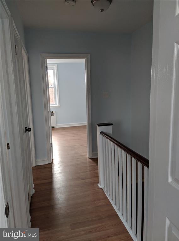 corridor with hardwood / wood-style flooring and radiator heating unit