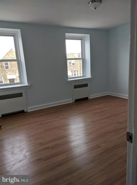 additional living space with dark hardwood / wood-style flooring and radiator