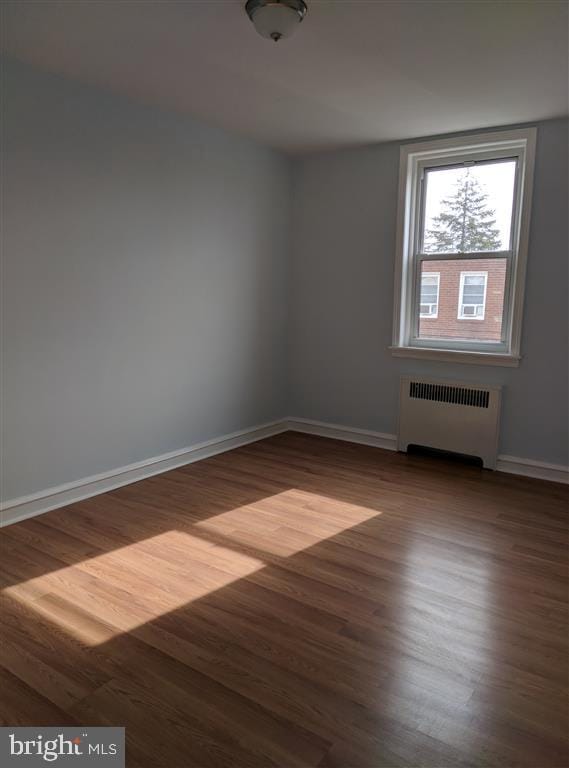 unfurnished room featuring radiator and hardwood / wood-style floors