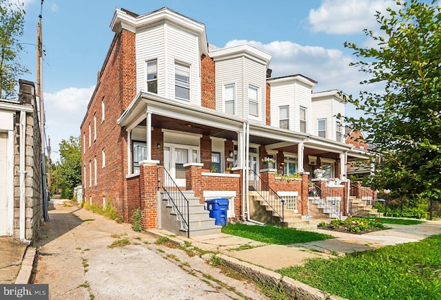 townhome / multi-family property with a porch and brick siding