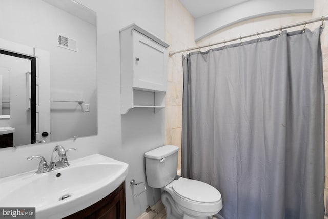 bathroom with curtained shower, vanity, and toilet