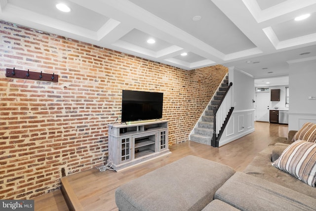 living room featuring light hardwood / wood-style floors, beamed ceiling, and brick wall