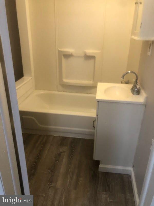 bathroom with vanity, hardwood / wood-style floors, and a tub to relax in