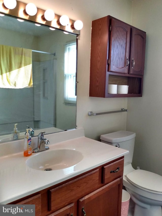 full bathroom featuring toilet, walk in shower, and vanity