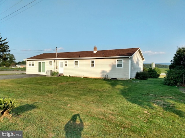 back of house featuring a lawn and a chimney