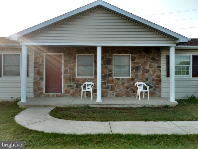 bungalow featuring stone siding and a porch