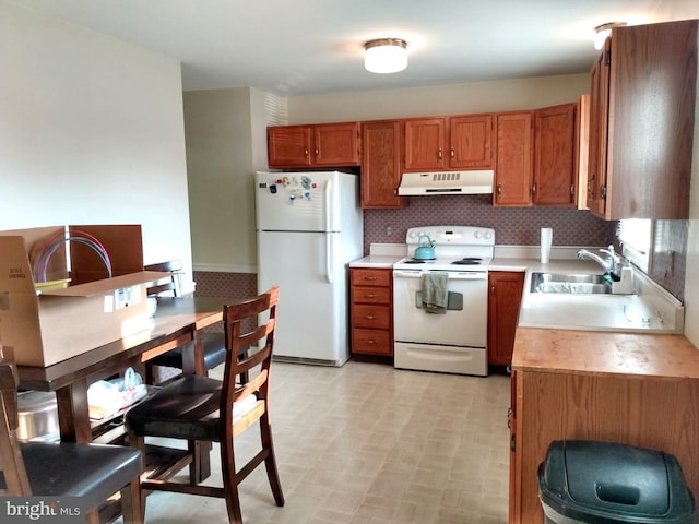 kitchen with white appliances, decorative backsplash, light countertops, under cabinet range hood, and a sink