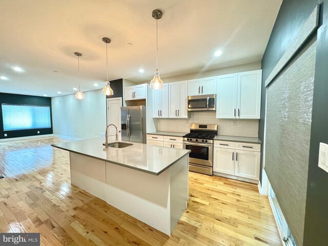 kitchen with white cabinetry, appliances with stainless steel finishes, sink, and light hardwood / wood-style flooring