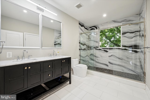 bathroom featuring tile patterned flooring, dual bowl vanity, a shower with door, and toilet