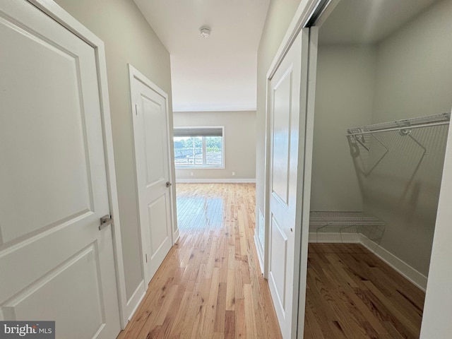 hall featuring light wood-style floors and baseboards