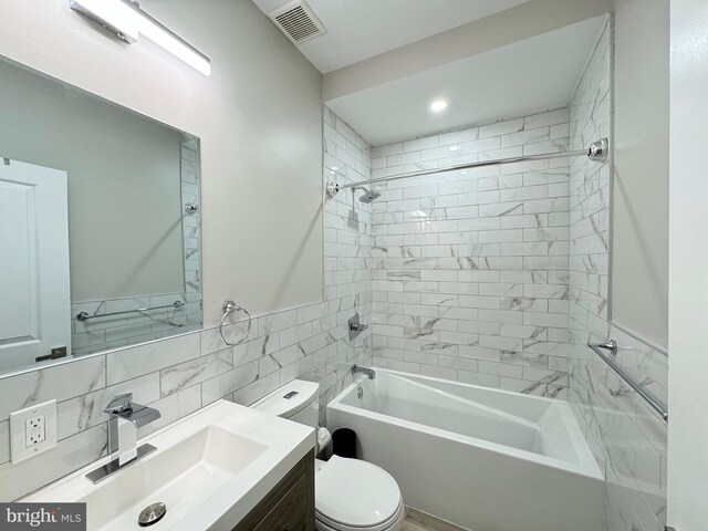 full bathroom with tiled shower / bath, toilet, vanity, and tile walls