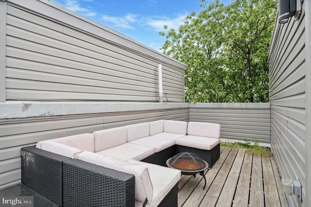 wooden deck featuring an outdoor living space with a fire pit