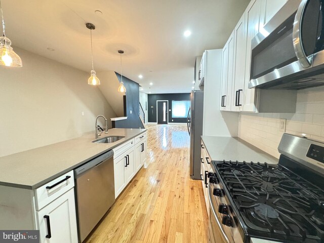 kitchen featuring sink, appliances with stainless steel finishes, light hardwood / wood-style flooring, decorative backsplash, and white cabinets