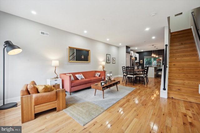 living area with light wood finished floors, baseboards, visible vents, stairway, and recessed lighting