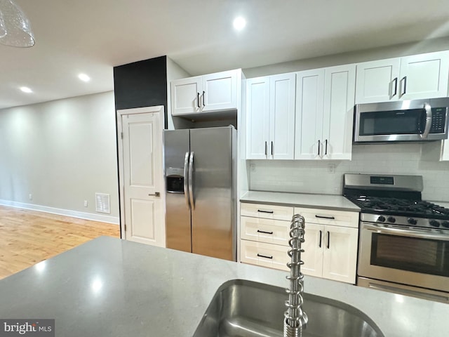 kitchen with tasteful backsplash, light countertops, appliances with stainless steel finishes, and white cabinets