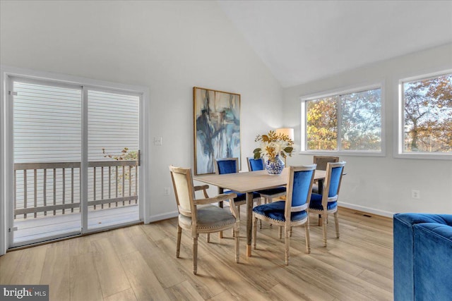 dining room with light wood-type flooring and vaulted ceiling