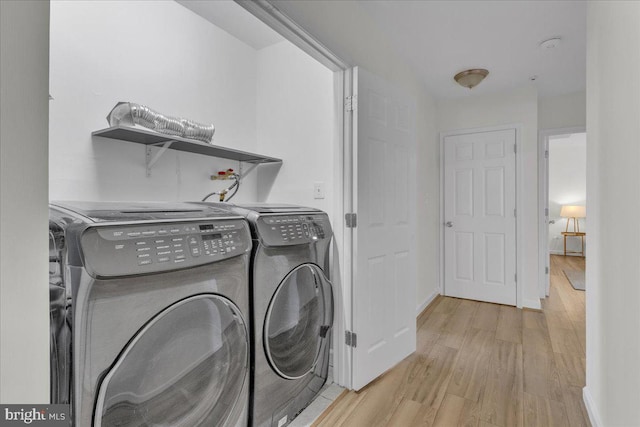 clothes washing area with light hardwood / wood-style floors and washer and dryer