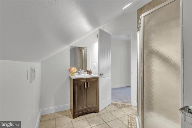 bathroom featuring lofted ceiling, a shower with door, tile patterned flooring, a textured ceiling, and vanity