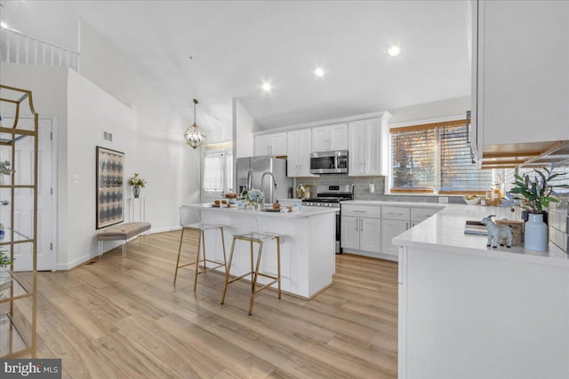 kitchen featuring light hardwood / wood-style floors, a kitchen breakfast bar, a kitchen island, white cabinetry, and appliances with stainless steel finishes