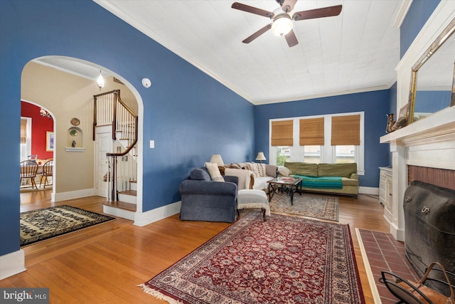 living area with ornamental molding, arched walkways, stairs, and wood finished floors