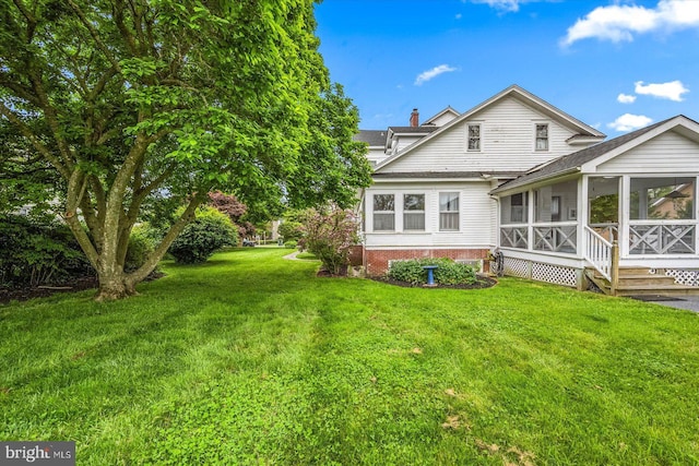 back of property featuring a lawn, a chimney, and a sunroom