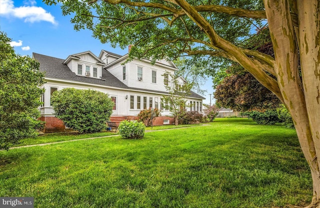 view of front of house featuring entry steps, a front lawn, a chimney, and a shingled roof