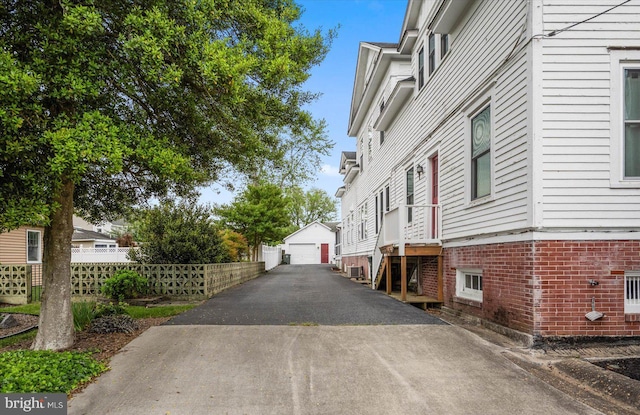 view of property exterior with a garage, fence, and an outdoor structure