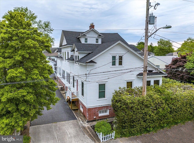 view of front of house featuring roof with shingles and a chimney