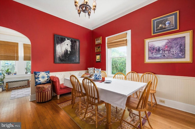 dining area with ornamental molding, a chandelier, wainscoting, and wood finished floors