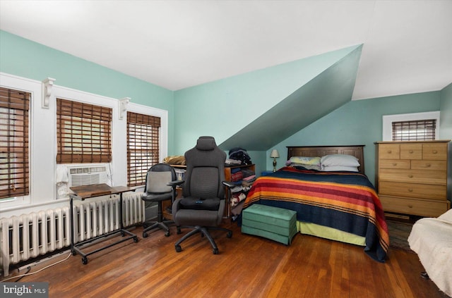 bedroom with vaulted ceiling, radiator heating unit, cooling unit, and wood finished floors