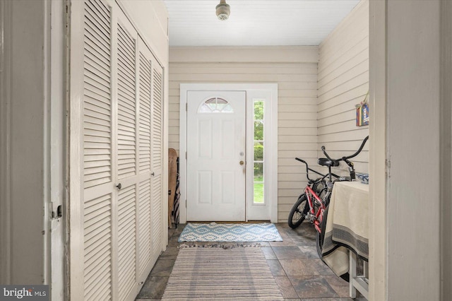 foyer entrance with wood walls and stone finish flooring