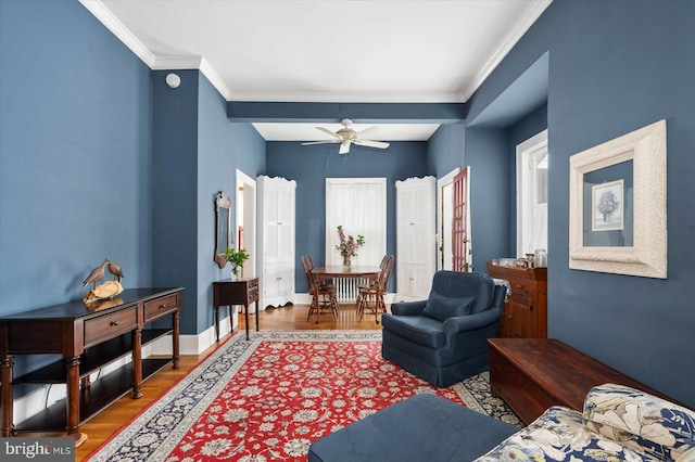 sitting room featuring ornamental molding, wood finished floors, a ceiling fan, and baseboards