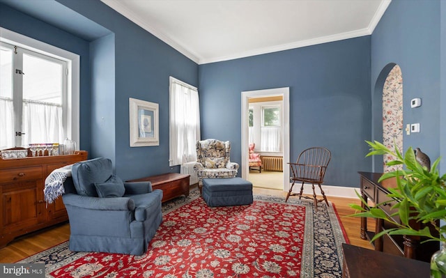 living area with ornamental molding, a wealth of natural light, and wood finished floors