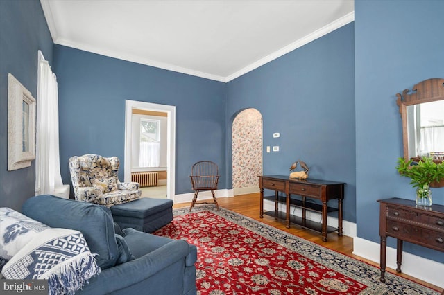 living room featuring baseboards, radiator heating unit, wood finished floors, and crown molding