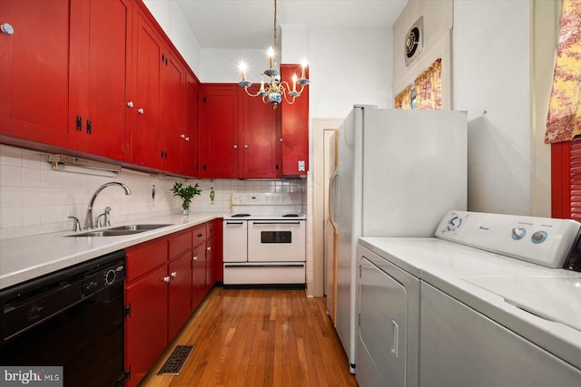 kitchen featuring light countertops, visible vents, red cabinetry, a sink, and white appliances