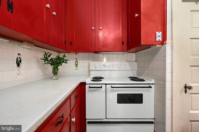 kitchen featuring light countertops, range with two ovens, and red cabinets