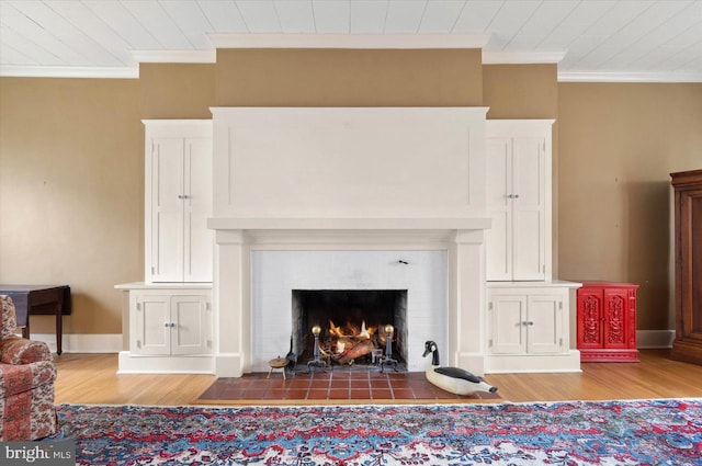 interior details with wood finished floors, ornamental molding, a fireplace with flush hearth, and baseboards